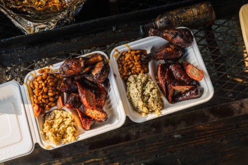 compostabale takeout container full of smoked bbq beans, sausage, chicken thighs & drumsticks, and dirty rice from a food truck or traveling smoker catering company - junk food stock pictures, royalty-free photos & images