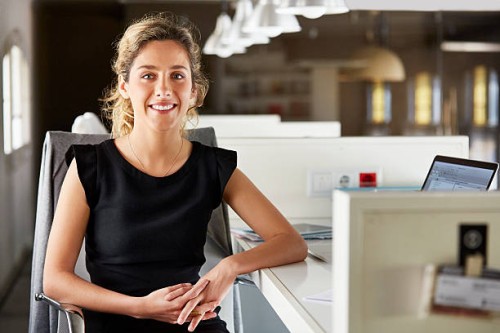 confident businesswoman sitting at desk - fashion stock pictures, royalty-free photos & images
