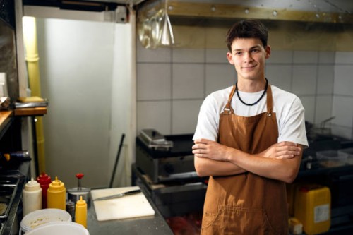 confident caucasian teenage boy working at a fast food restaurant kitchen - junk food stock pictures, royalty-free photos & images