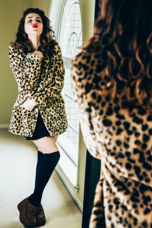 confident woman looking in mirror, making kissy face in leopard print jacket - fashion stock pictures, royalty-free photos & images