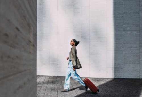 confident woman walking with red suitcase in modern urban setting - travel stock pictures, royalty-free photos & images