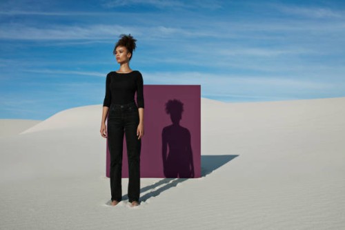 confident young fashion model standing against purple placard at white desert - fashion stock pictures, royalty-free photos & images