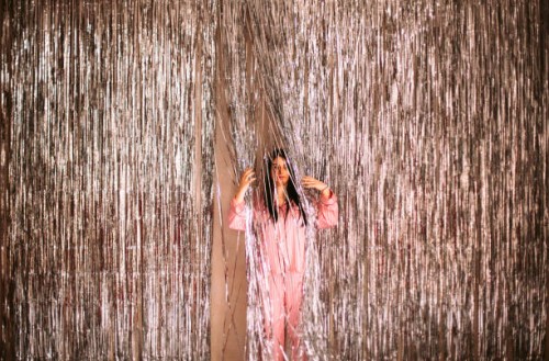 confused young woman wearing pajama standing amidst glittering tinsel during christmas holidays - home decoration stock pictures, royalty-free photos & images