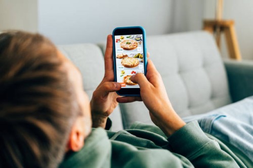 contactless food delivery. mobile app on phone screen. person holds smartphone in hand - food stock pictures, royalty-free photos & images