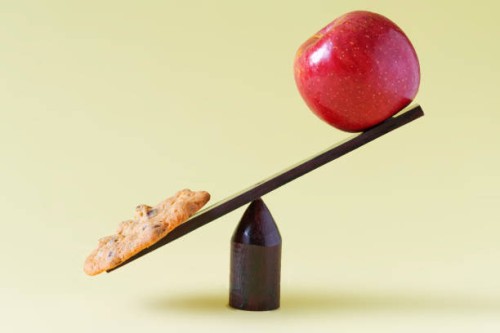 cookie and apple on scale - junk food stock pictures, royalty-free photos & images