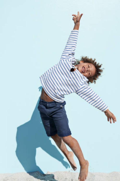 cool and cute boy jumping on beach with backdrop - fashion stock-fotos und bilder
