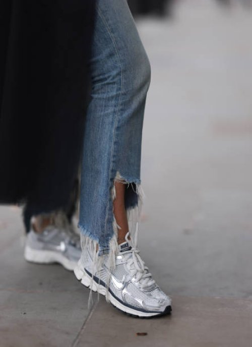 Corina Mihaila Larpin seen wearing a black and white striped long Monse Jaket, light blue denim Jeans from R13, and white, silver and black Nike...