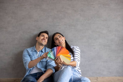 couple at home thinking about painting the walls and holding a color swatch - home decoration stock pictures, royalty-free photos & images