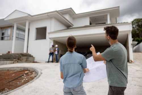 couple building their dream house and pointing at details while holding blueprint - home decoration stock pictures, royalty-free photos & images
