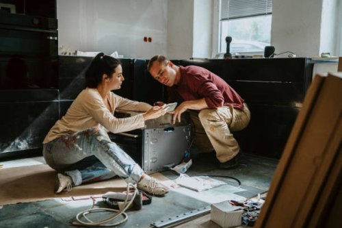 couple discussing over mobile phone while renovating kitchen at home - home decoration stock pictures, royalty-free photos & images