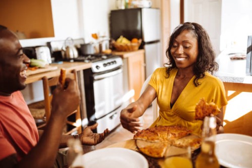 couple eating a pizza in the kitchen togetherness - junk food stock pictures, royalty-free photos & images