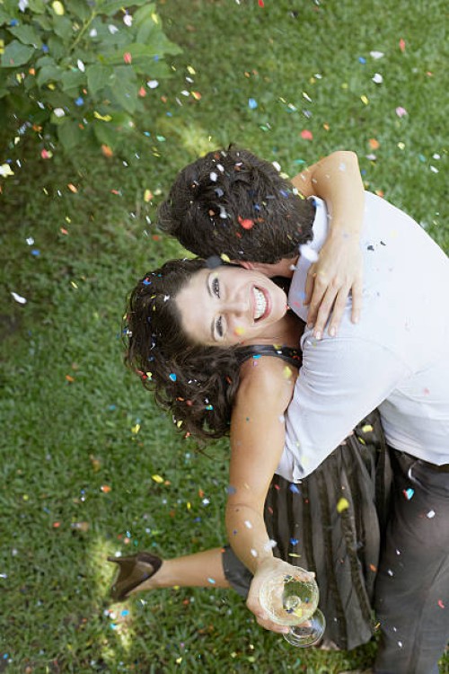 couple embracing outdoors with white wine and confetti smiling - garden decoration stock pictures, royalty-free photos & images