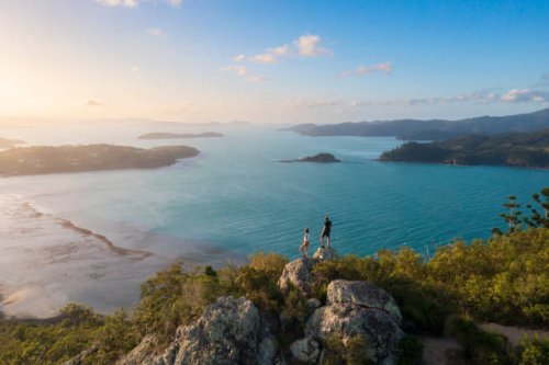 couple enjoying the view on top mountain overlooking whitsundays ocean - travel stock pictures, royalty-free photos & images