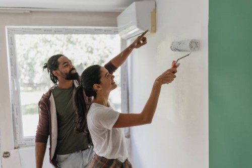 couple enthusiastically painting together indoors - home decoration stock pictures, royalty-free photos & images