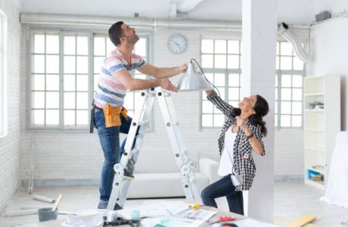 couple hanging a lamp in new apartment - home decoration stock pictures, royalty-free photos & images