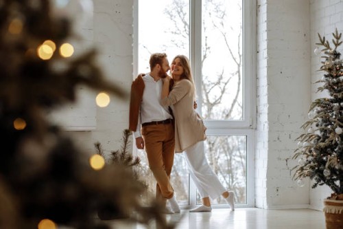 couple in love hugging near big window at home with christmas interior - fashion stock pictures, royalty-free photos & images