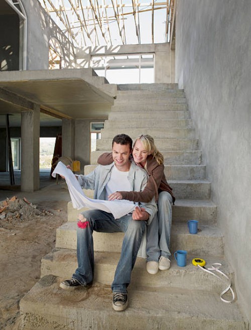 couple looking at blueprints on staircase of house under construction - home decoration stock pictures, royalty-free photos & images