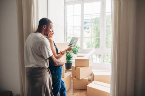 couple looking at color swatch while leaning by wall at new home - home decoration stock pictures, royalty-free photos & images