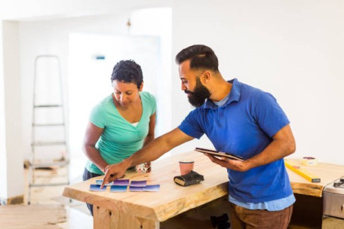 couple looking at paint samples and a tablet computer - home decoration stock pictures, royalty-free photos & images