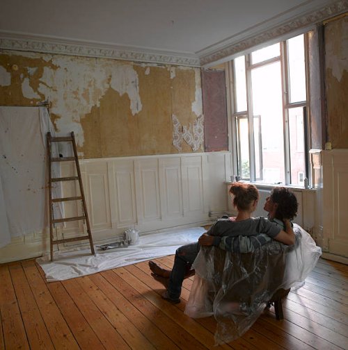 couple looking at partly decorated wall - home decoration stock pictures, royalty-free photos & images