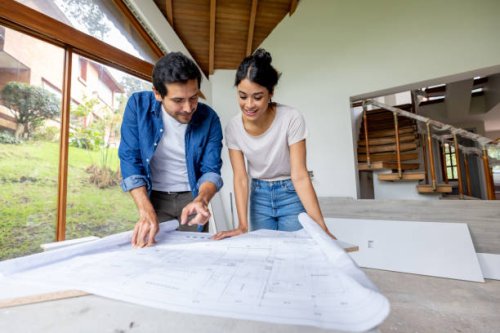 couple looking at the blueprints while renovating their house - home decoration stock pictures, royalty-free photos & images