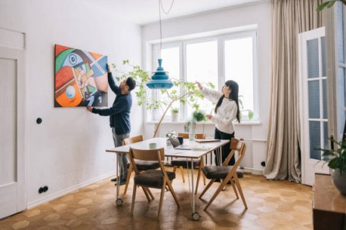couple looking for perfect place to hang their painting - home decoration stock pictures, royalty-free photos & images