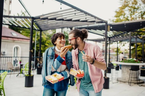 couple on the street eating fast food - junk food stock pictures, royalty-free photos & images