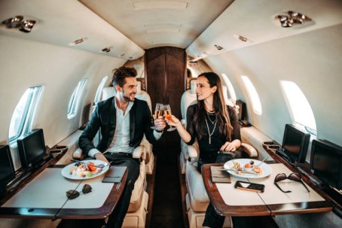 couple réussi faire un toast avec des verres de champagne tout en ayant des canapés à bord d’un avion privé - travel photos et images de collection