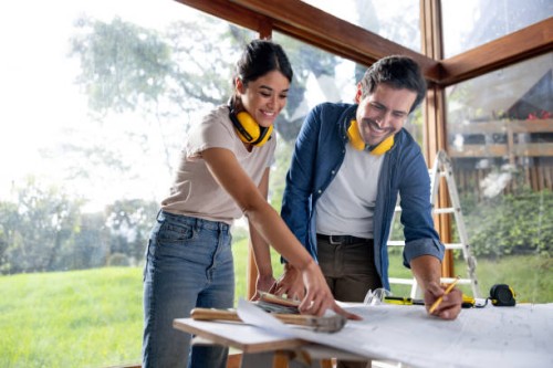 couple remodeling their house and looking at the blueprints - home decoration stock-fotos und bilder