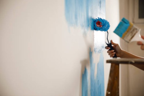couple repainting the white wall into blue color - home decoration stock pictures, royalty-free photos & images