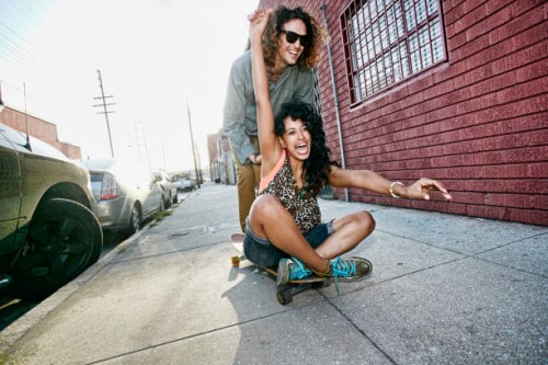 couple riding skateboard on city street - fashion stock pictures, royalty-free photos & images