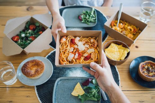 couple sharing takeaway meal at dining table - junk food stock pictures, royalty-free photos & images