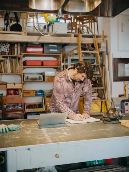 craftsman writing in book while taking order through phone in antique shop - home decoration stockfoto's en -beelden