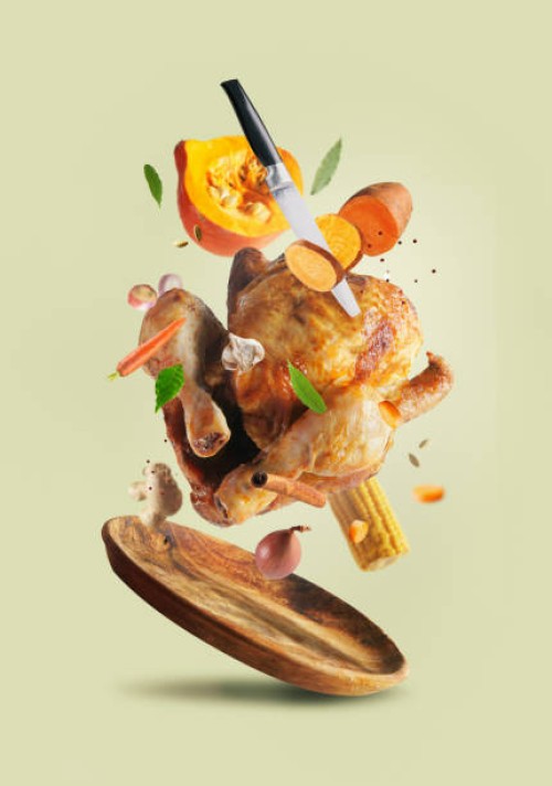 creative thanksgiving food with whole roasted turkey, sweet potato, knife, carrot, pumpkin, onion, garlic and herbs flying in the air over wooden plate at pale beige background. - food stock pictures, royalty-free photos & im