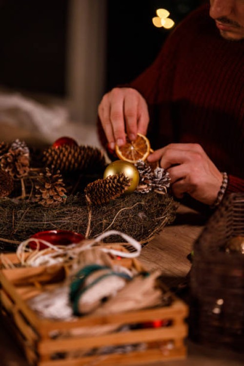 creative young man decorating a christmas wreath with rustic ornaments - home decoration stock pictures, royalty-free photos & images