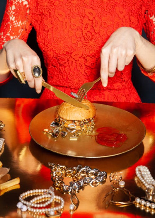 crop woman eating burger with jewelry on dark background - food stock-fotos und bilder