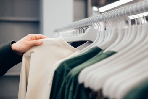 cropped hand of man holding shirt in shop - fashion stock pictures, royalty-free photos & images