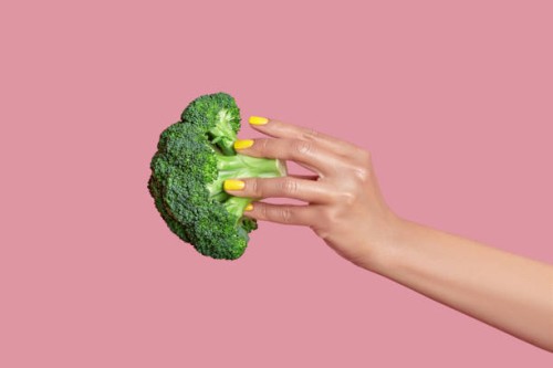 cropped hand of woman holding broccoli against pink background,kyiv,ukraine - food photos et images de collection