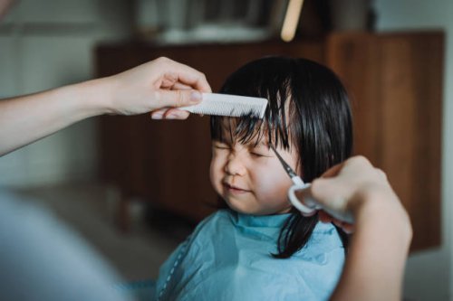 cropped hands of young asian mother cutting hair of her little daughter at home - hairstyle stock-fotos und bilder