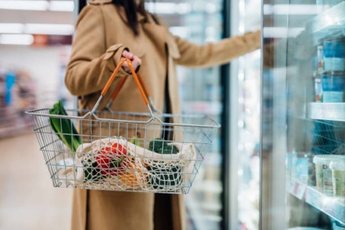 cropped shot of woman carrying shopping basket and shopping groceries in supermarket - food stockfoto's en -beelden