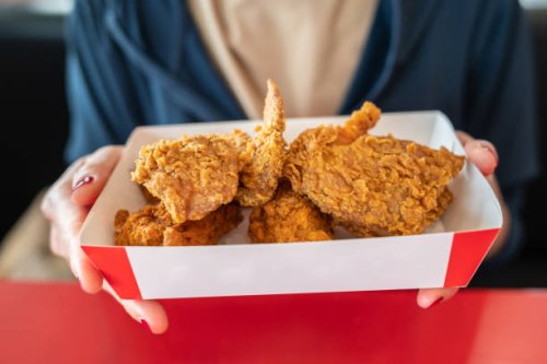 cropped shot of woman holding a paper box with pieces of fried chicken before eating. - junk food stock pictures, royalty-free photos & images