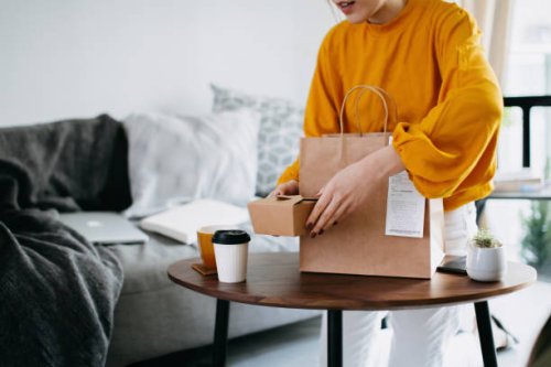 cropped shot of young asian woman holding boxes of home delivery takeaway food that have just arrived to share, serving on the coffee table. eating at home concept - junk food stock pictures, royalty-free photos & images