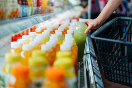cropped shot of young asian woman shopping for fresh fruit juice from refrigerated shelves in supermarket, taking out a bottle of freshly squeezed green juice into a shopping basket. healthy eating, go green lifestyle - food 