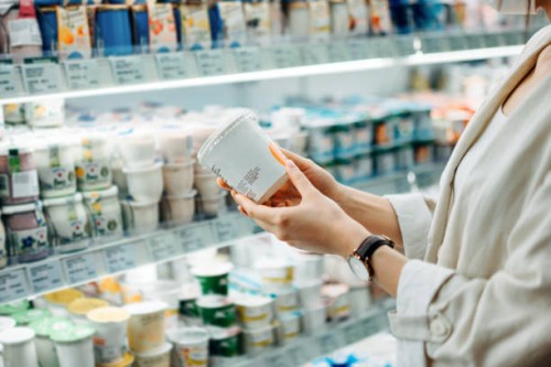 cropped shot of young asian woman shopping in the dairy section of a supermarket. she is reading the nutrition label on a container of fresh organic healthy natural yoghurt - food stock pictures, royalty-free photos & images