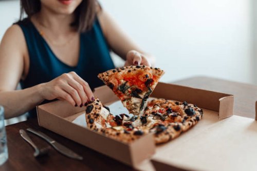 cropped shot of young woman eating pizza from pizza box at. food delivery. takeaway food. - junk food stock pictures, royalty-free photos & images