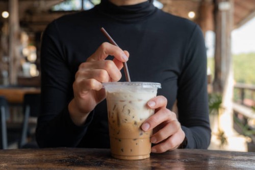 cropped shot view of asian woman holding a plastic cup of iced milk coffee before drink. - junk food stock pictures, royalty-free photos & images