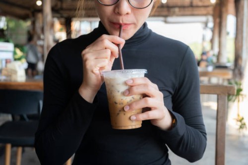 cropped shot view of young asian woman drinking iced milk coffee in coffee shop. - junk food stock pictures, royalty-free photos & images