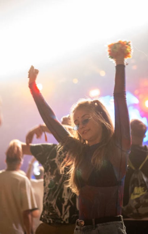 crowd of people attending a musical performance. punk girl dancing. bright light beams coming from the stage - concert stock pictures, royalty-free photos & images