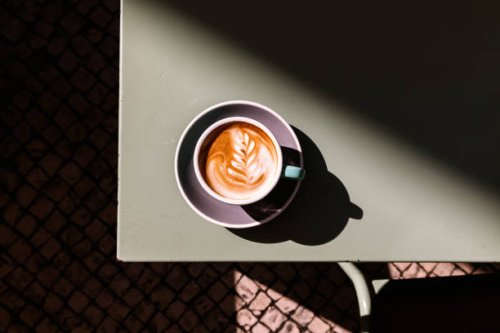 cup of cappuccino with latte art on the table, directly above view - coffee stockfoto's en -beelden