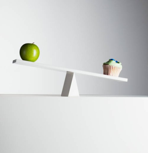 cupcake tipping seesaw with green apple on opposite end - junk food stock pictures, royalty-free photos & images